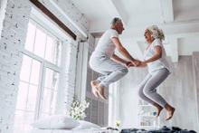 Older Persons Shared Ownership - couple jumping for joy on a bed